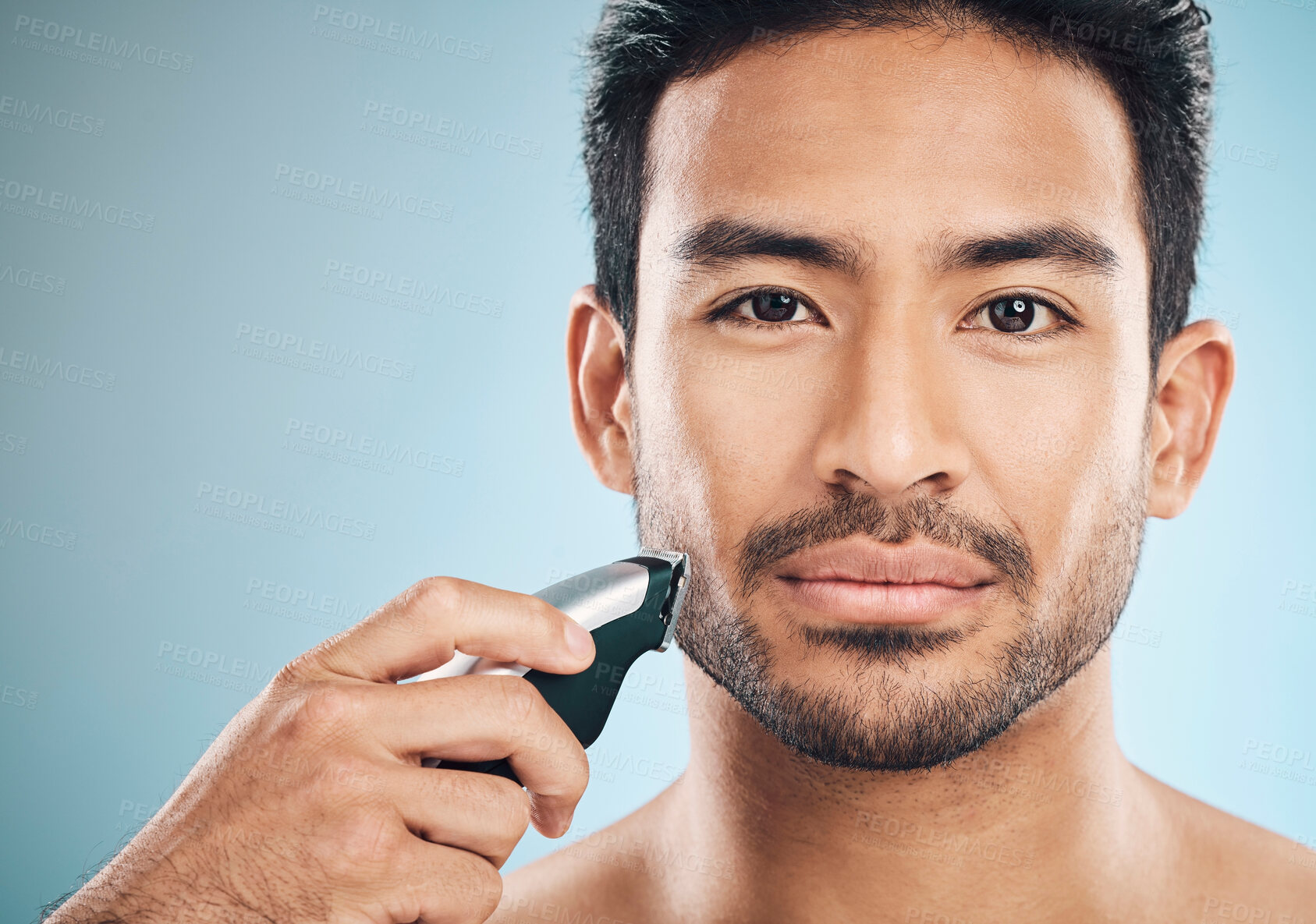 Buy stock photo Portrait, shave and electric razor with a man in studio on a blue background for personal hygiene or grooming. Face, wellness or cosmetics with a confident young male in the bathroom for hair removal