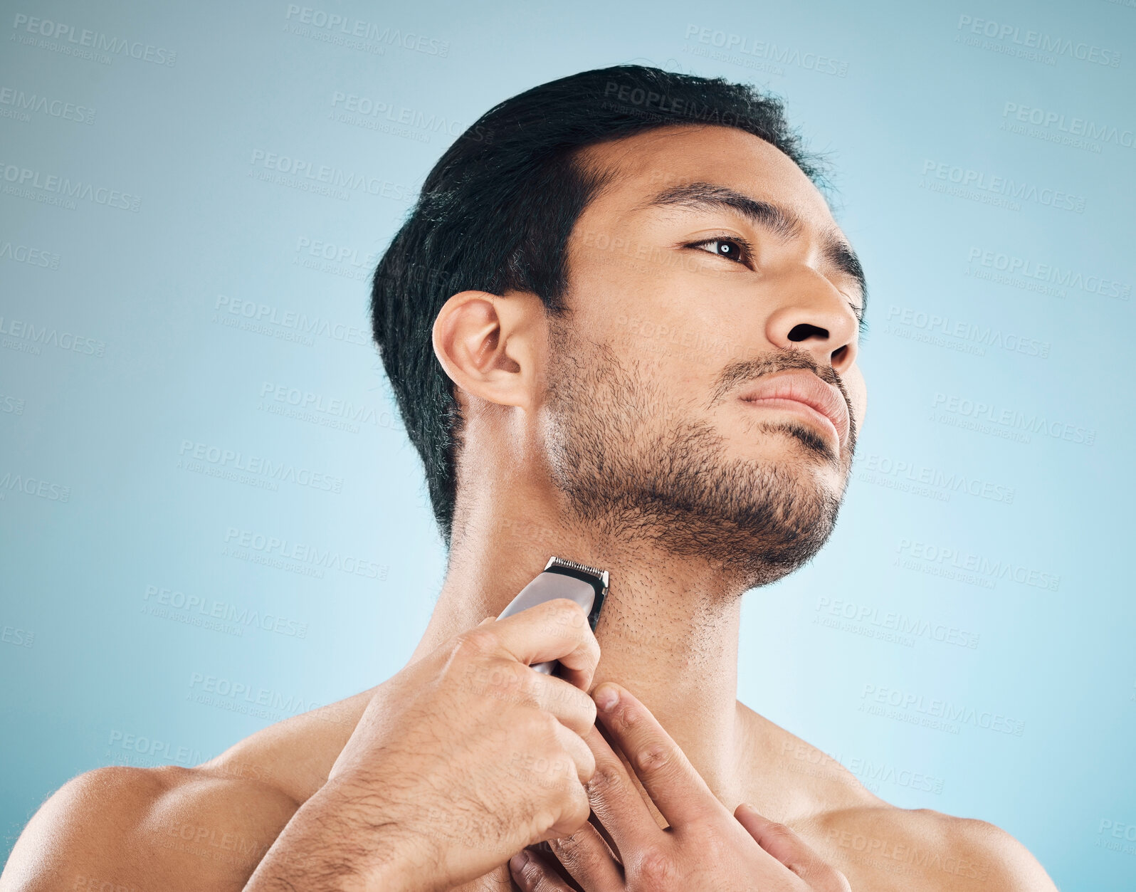 Buy stock photo Face, shaving and electric razor with a man in studio on a blue background for personal hygiene, skincare or grooming. Beauty, wellness or cosmetics with a young male in the bathroom for hair removal