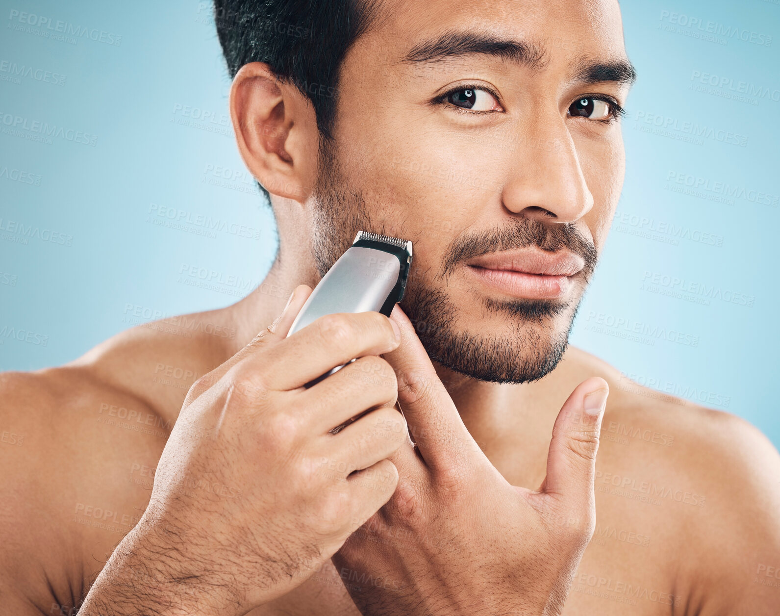 Buy stock photo Portrait,, electric shaving and grooming with a man in studio on a blue background for personal hygiene or skincare. Face, wellness and cosmetics with a young male in the bathroom for hair removal