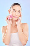 Woman, beauty and rose for skincare in studio, eco plant cosmetics and natural aesthetic on blue background. Face, female model and thinking of pink flowers, sustainable shine and floral dermatology