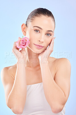 Buy stock photo Woman, portrait and rose for skincare in studio, eco cosmetics and natural aesthetic facial on blue background. Face, female model and beauty of pink flowers, sustainable shine and floral dermatology