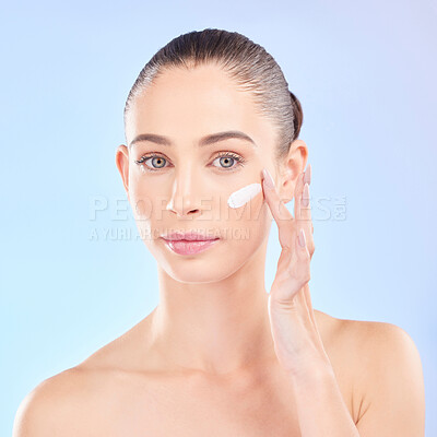 Buy stock photo Face, skincare and woman with cream in studio isolated on a blue background. Portrait, dermatology and serious model with creme, cosmetic or sunscreen moisturizer for health, aesthetic or wellness