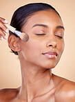 Beauty, makeup and foundation with woman and brush in studio for facial, relax and self care. Cosmetics, product and tools with face of model on brown background for glow, skincare and dermatology