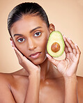 Avocado, beauty and woman in portrait for healthy face and natural skincare on studio brown background. Young indian person or model with green fruits, vitamin c benefits and dermatology or cosmetics