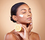 Woman, lemon and cream for beauty, natural skincare product and cosmetics or vitamin c benefits and thinking. Person sleeping with face lotion, fruits and skin dermatology on brown, studio background