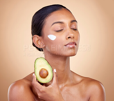 Buy stock photo Beauty, cream and skincare with woman and avocado in studio for product, fruit and natural cosmetics. Spa, facial and lotion with face of model on brown background for vitamin c and self care