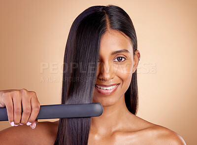 Buy stock photo Portrait, hair and flat iron with a woman in studio on a beige background for beauty or style. Face, smile and haircare with happy young female model using a straightener appliance for natural care