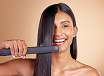 Portrait, hair and flat iron with a model woman in studio on a beige background for beauty or style. Face, smile and haircare with happy young female using a straightener appliance for natural care
