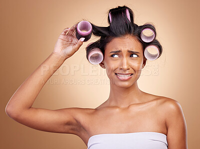 Buy stock photo Hair care, problem and a woman with rollers on a studio background for fail of curls. Sad, beauty and a young Indian model or girl with gear for a curly hairstyle mistake isolated on a backdrop