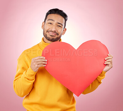 Buy stock photo Heart, happy and love with portrait of man in studio for romance, date and valentines day. Kindness, support and hope with person and sign on pink background for wellness, peace and creative mockup