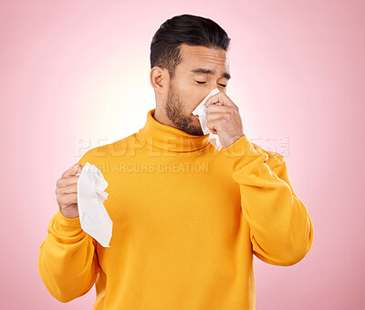 Buy stock photo Sick, tissues and man blowing his nose in a studio with a cold, flu or sinus allergies. Illness, hayfever and Indian male person with paper napkin for virus or infection symptoms by a pink background