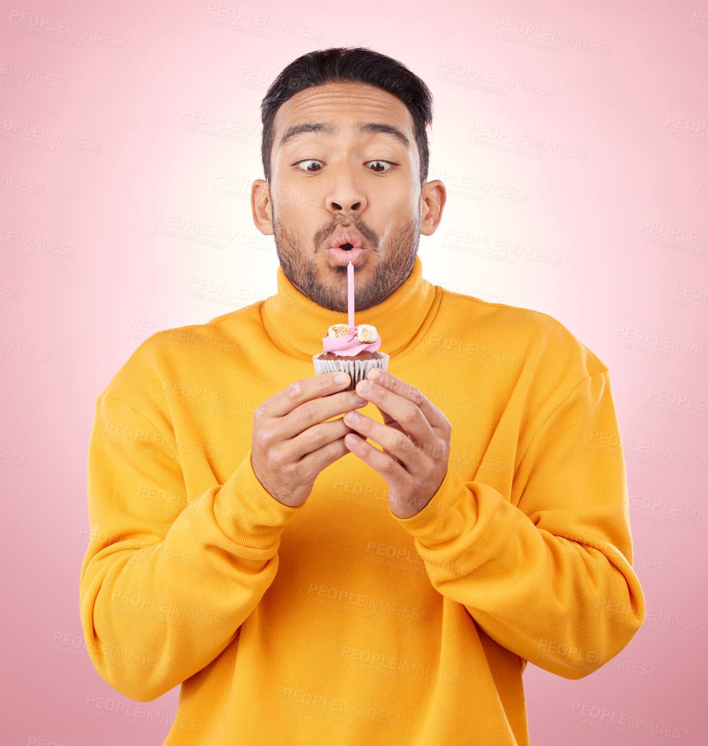 Buy stock photo Food, cupcake and man blowing candle in studio for celebration, party and dessert. Birthday, wish and flame with face of male person and cake on pink background for surprise, candy and gift mockup