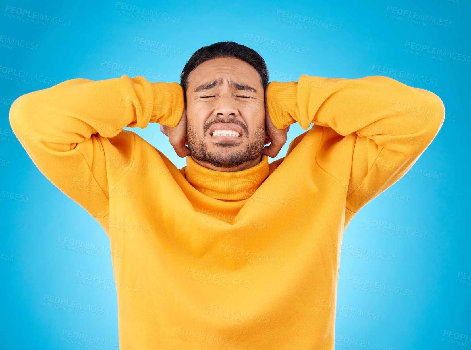 Buy stock photo Stress, headache and hands on ears of man in studio with noise, complaint or crisis on blue background. Anxiety, migraine and frustrated male with vertigo, brain fog or tinnitus, depression or trauma