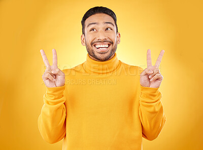 Buy stock photo Peace, hands and happy asian man in studio with thank you, vote or feedback on yellow background. V, sign and Japanese male model with emoji fingers, smile and good mood, vibes or positive attitude