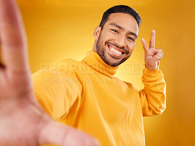 Buy stock photo Selfie, peace sign and happy portrait of a man in studio with hand, emoji and a smile. Male asian fashion model on a yellow background with a positive mindset for social media profile picture update