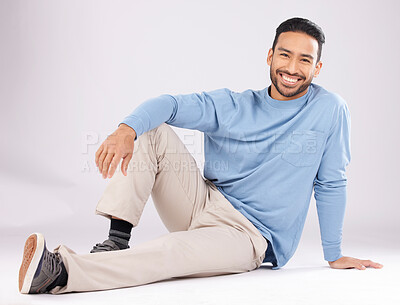 Buy stock photo Portrait, fashion and happy man on the floor in studio isolated on a white background. Style, smile and Asian person from Cambodia in casual clothes, trendy aesthetic or confidence to relax on ground