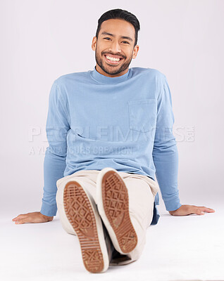 Buy stock photo Portrait, fashion and man smile on the floor in studio isolated on a white background. Style, happy and Asian person from Cambodia in casual clothes, trendy aesthetic or confidence to relax on ground