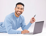Laptop, credit card and asian man portrait on studio floor for ecommerce, sale or cashback on grey background. Online shopping, face and Japanese guy customer smile for loan, payment or sign up promo