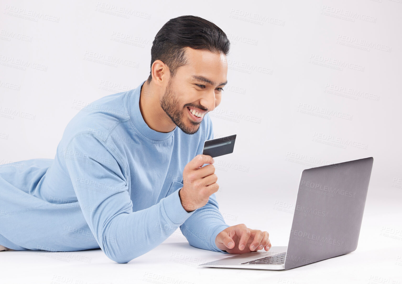 Buy stock photo Man, studio and laptop with credit card, e commerce or payment information with smile by white background. Young asian guy, floor and happy with fintech, sale or deal with virtual customer experience