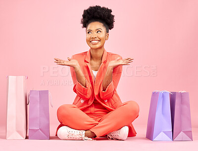 Buy stock photo Woman, shopping bag and smile on studio floor, idea or thinking for deal, sale or choice by pink background. African gen z girl, happy or decision for fashion, open palm or retail customer experience