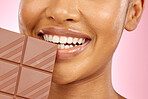 Woman, mouth and chocolate in studio closeup with smile, eating and skin glow for beauty by pink background. Girl, model and diet with sweets, snack or candy for cheat day, cosmetics and headshot