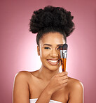Portrait, makeup and black woman with brushes, skincare and dermatology against a pink studio background. Female person, aesthetic or model with cosmetic tools, natural beauty or shine with self care