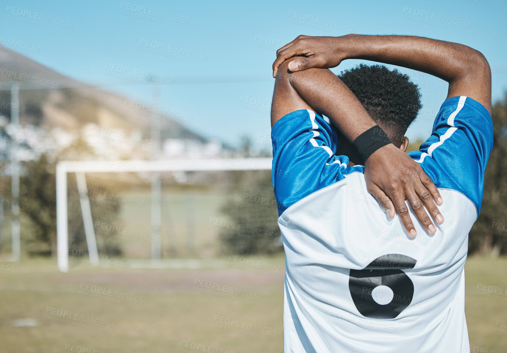 Buy stock photo Man, soccer and stretching arm in fitness commitment for match, game or training on grass field outdoors. Rear view of person or sports athlete in body warm up for healthy start or football practice