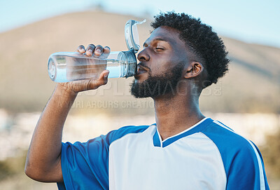 Buy stock photo Black man, fitness or soccer player drinking water in training, exercise or workout in football field. Thirsty, sports or tired athlete on resting break with a healthy beverage for energy to relax