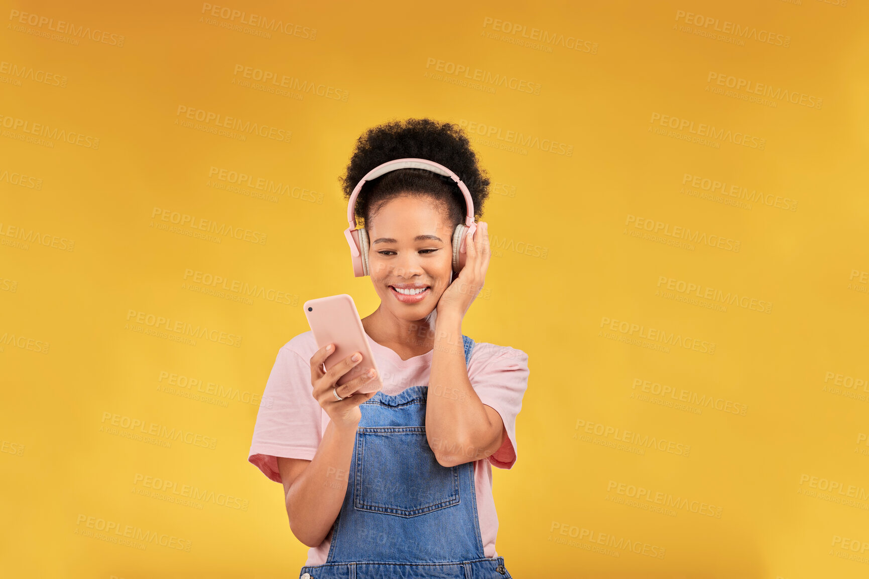 Buy stock photo Happy, music and a black woman with a phone on a studio background for a podcast or audio. Smile, space and an African girl with headphones and a mobile for an app, streaming and listening to radio