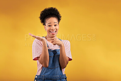 Buy stock photo Portrait, marketing and a black woman pointing to her palm for the promotion of a product on a yellow background in studio. Smile, advertising or space with a happy young female brand ambassador