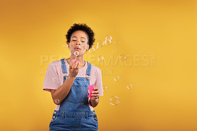 Buy stock photo Blowing bubbles, woman and fun in studio while playful for birthday or party celebration. Black female model person with liquid soap, natural beauty and fashion on a yellow background with space