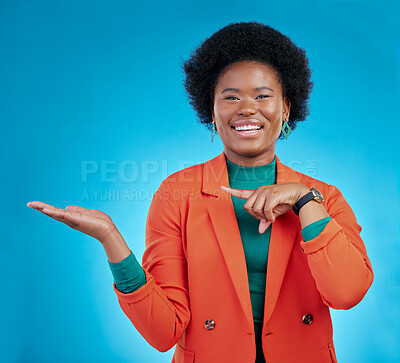 Buy stock photo Happy black woman, portrait and pointing to palm for advertising against a blue studio background. Face of African female person show advertisement in marketing, list or sale discount on mockup space