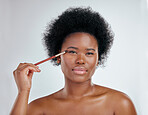 Black woman, portrait and makeup brush on eyes for skincare beauty against a white studio background. Face of African female person applying eye product, cosmetics or lashes for facial treatment