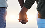 Couple, holding hands and together outdoor at the beach with love, care and commitment. Closeup of a man and woman on vacation, holiday or sunset travel adventure in nature with support and trust