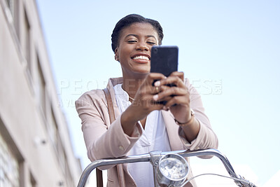 Buy stock photo Business woman in city with bicycle, phone and smile on commute, checking location or social media. Eco friendly transport bike, cycling and happy African girl typing with mobile app on work travel.