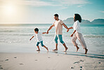 Sunset, flare and a family holding hands on the beach while walking during travel, vacation or bonding. Love, children and parents on sand at the coast by an ocean or sea for summer holiday fun