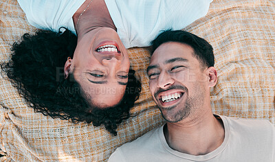 Buy stock photo Face, picnic and smile with a couple laughing on a blanket from above, lying on the ground while on a date. Love, happy or funny with a man and woman bonding together for romance on valentines day