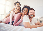Happy family, portrait and relax on a bed, bond and having fun on the weekend in their home together. Interracial, love and face of playful children with parents in a bedroom, smile and playing games