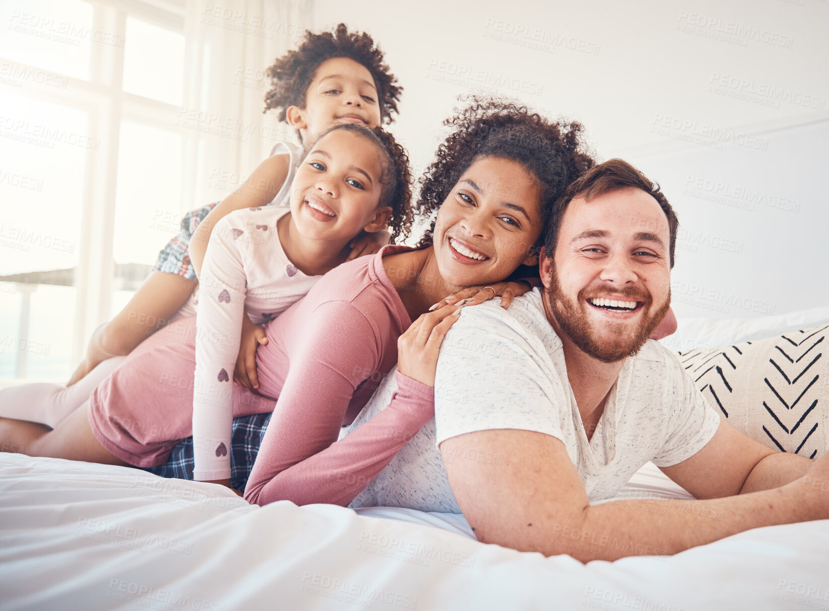Buy stock photo Happy family, portrait and relax on a bed, bond and having fun on the weekend in their home together. Interracial, love and face of playful children with parents in a bedroom, smile and playing games