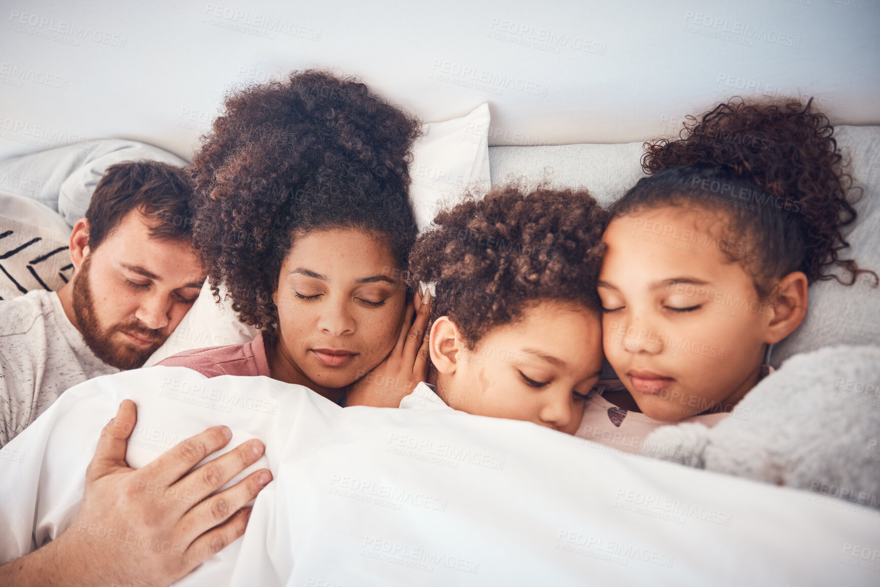 Buy stock photo Family, sleeping and together in bed at home for security, bonding and comfort. Healthy, mixed race and a man, woman and children nap, dream and rest or relax in a bedroom with love, care and peace