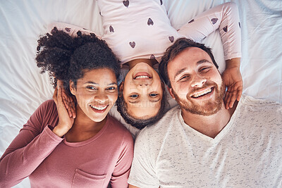 Buy stock photo Smile, happy family and portrait on bed at home for quality time, bonding or morning routine. Above, mixed race and face of a man, woman and girl kid together in a bedroom with love, care and comfort
