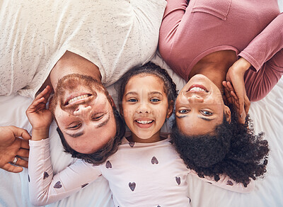 Buy stock photo Happy family, smile and portrait on bed at home for quality time, bonding or morning routine. Above, mixed race and face of a man, woman and girl kid together in a bedroom with love, care and comfort