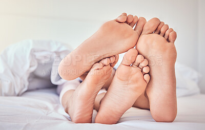 Buy stock photo Feet, love and a couple in bed to relax in the morning while bonding in their home for trust or support. Bedroom, sleeping or dreaming with a man and woman resting closeup under a blanket in a house