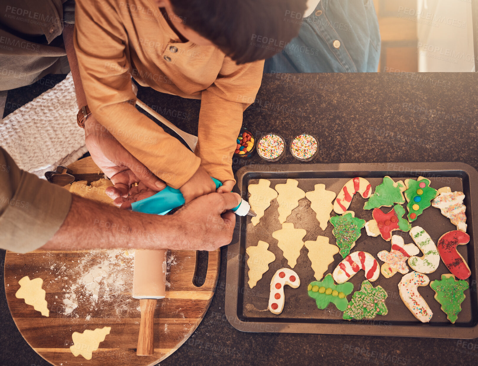 Buy stock photo Christmas, above and a family baking cookies, help with food and process of decoration. Hands, child and teamwork for icing sweet dessert or biscuits for a festive holiday in the kitchen together