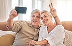 Happy senior couple, peace sign and selfie in relax on living room sofa for photograph, memory or vlog at home. Elderly man and woman smile for picture, photo or social media on lounge couch together