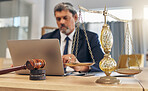 Scales, gavel and man in office with laptop at law firm, online research for court advice and senior lawyer at desk. Judge, attorney or legal consultant job with justice, computer and internet search
