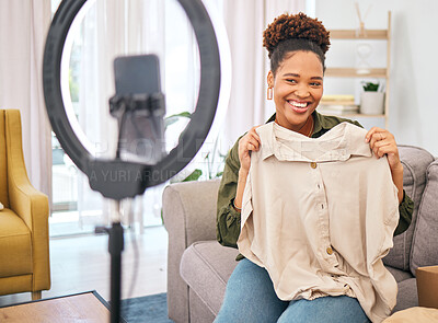 Buy stock photo Fashion, live streaming and a black woman influencer unboxing a clothes outfit in her home. Social media, brand deal and a happy female content creator recording a broadcast for subscription service