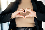 Closeup of a businesswoman with a heart shape in the office  for care, support and valentines day. Zoom of a professional female person with a love hand gesture, sign or emoji in the workplace.