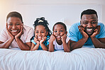 Smile, portrait and black family in bed happy, bond and relax in their home on the weekend. Love, face and children with parents in bedroom playful, free and chilling while enjoying morning together