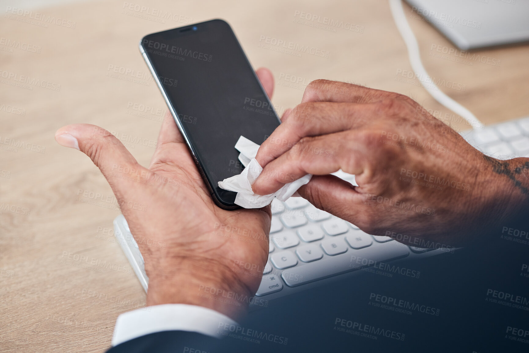 Buy stock photo Closeup of man wipe his phone with a tissue to prevent germs, bacteria or dirt in his office. Technology, hands and male person cleaning cellphone screen for hygiene, health and wellness at workplace